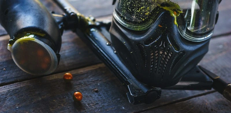 Paintballmasker och markörer uppställda vid utrustningsbod